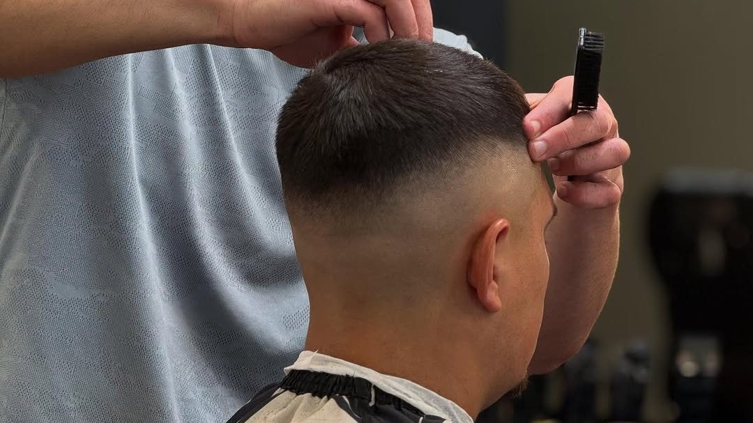 A barber at Aliana Barbershop finishing a fade with a straight razor