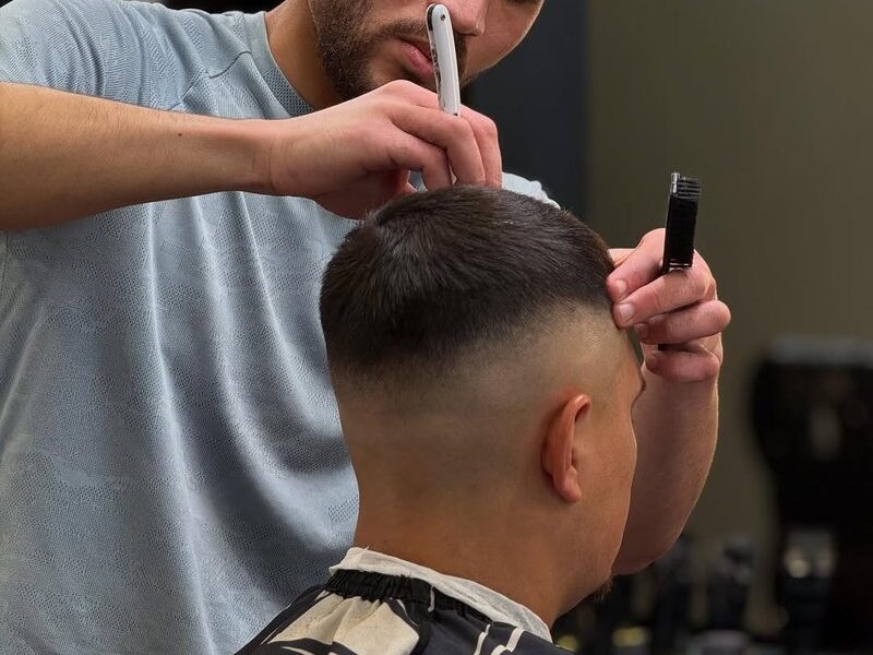 A barber detailing a skin fade with a straight razor at Aliana Barbershop