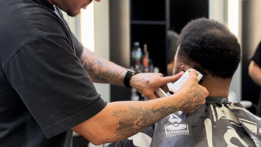 A barber at Aliana Barbershop cleaning up a client's fade with clippers